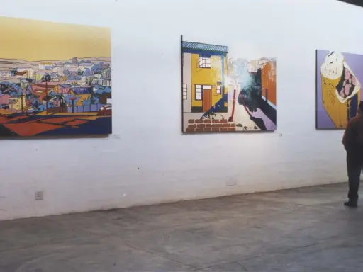 A person contemplates vibrant, stylized paintings in an art gallery, each piece curating meaning through bold colors and urban landscapes.