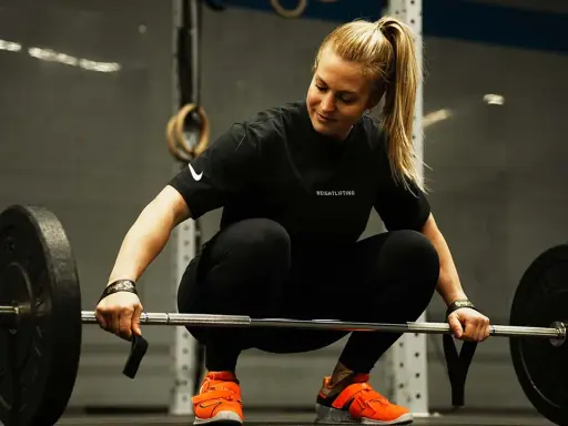 Eine Frau in Sportkleidung bereitet sich auf das Gewichtheben vor. Eine **1 Woche Trainingspause sinnvoll** für Regeneration und neue Kraft.