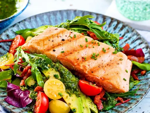 Saftiges Lachsfilet, indirekt gegrillt, serviert mit einem bunten Salat aus Tomaten, Avocado und knackigem Grün.