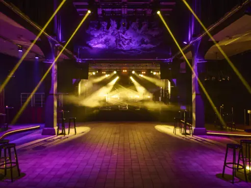 Scenljus och rök fyller en tom lokal i slakthusområdet Stockholm, redo för en kväll med musik och fest.