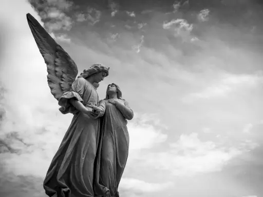 Zwei Engelsstatuen blicken sich an. Einer hält ein Buch. Die Frage, wie viele Engel es gibt, bleibt im Himmel offen.