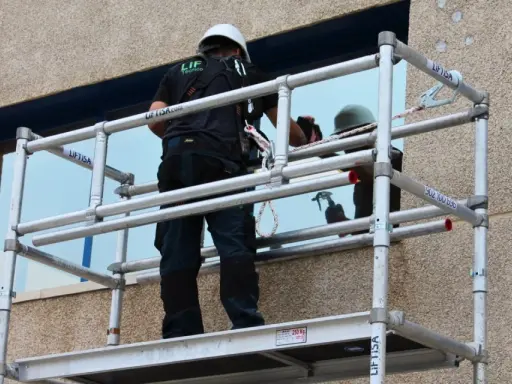 Técnico trabajando en un andamio, revisando las partes de un andamio para asegurar su estabilidad.