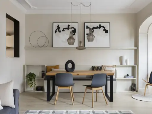Comedor moderno con paredes color beige arena, mesa de madera, sillas grises y arte abstracto.