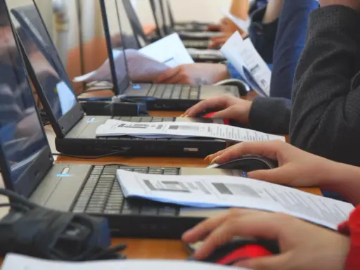 Uczniowie klasy 4 na lekcji informatyki pracują przy komputerach, korzystając z myszek i dokumentów.