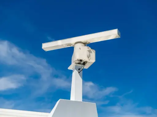 Antenne blanche sur un mât, sous un ciel bleu. Elle ressemble à un radar, mais pourrait aussi servir pour la communication satellite.