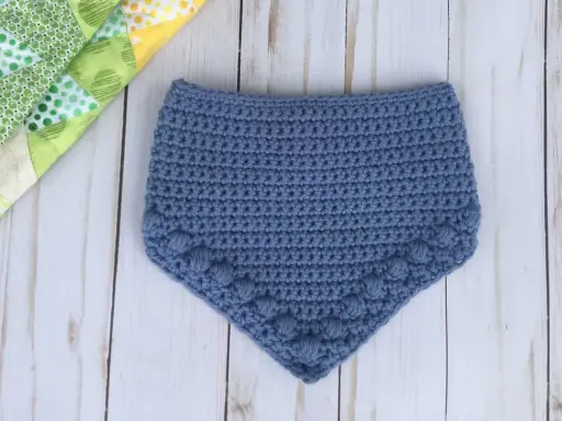 Babero azul tejido a crochet con detalle de pompones. Patrones baberos crochet instrucciones para crear esta linda prenda.