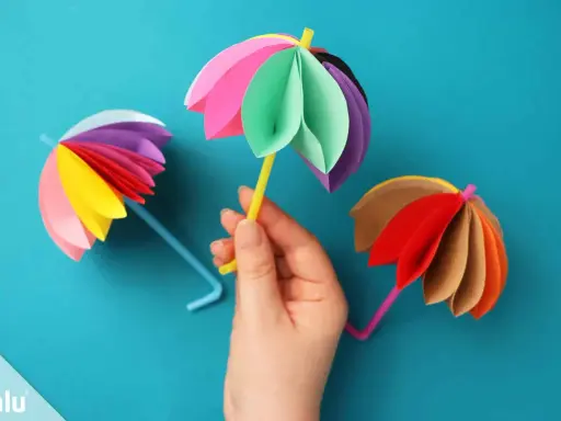 Bunte Regenschirme aus Tonpapier, perfekt zum Basteln mit Kindern. Ein gelber Schirm wird von einer Hand gehalten.
