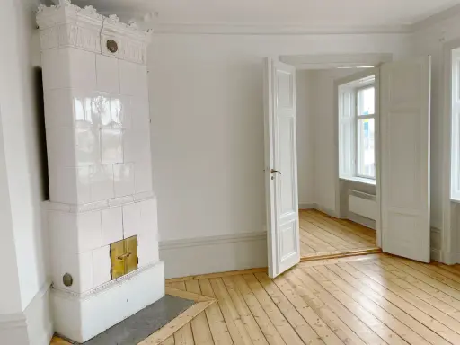 Vitt, vackert kakelugn med mässingsluckor. Tänk att elda i kakelugn en kall vinterdag.