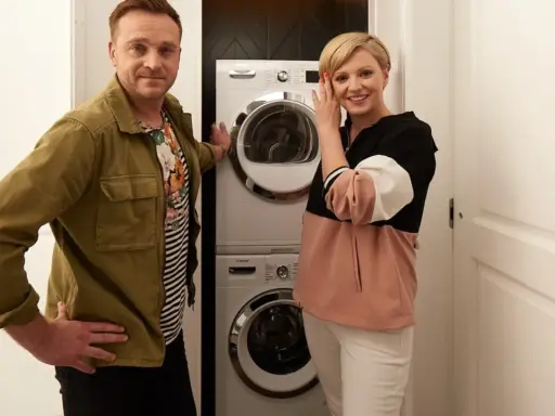 Para prezentuje pralkę i suszarkę w kuchni.