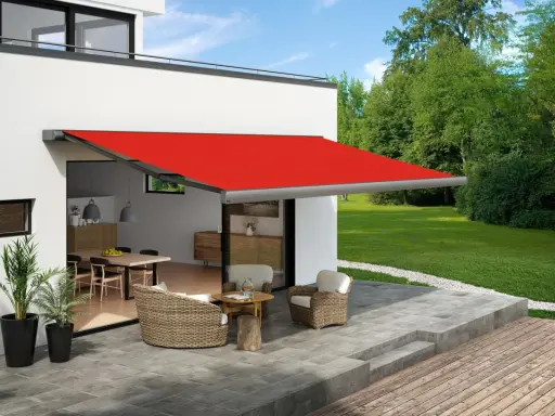 Toldo rojo extendido sobre un patio con muebles de mimbre, ofreciendo ideas para dar sombra en un patio.