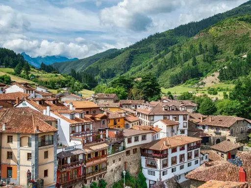 Potes, un pintoresco pueblo en los Picos de Europa, con casas de tejados rojos y montañas verdes de fondo.