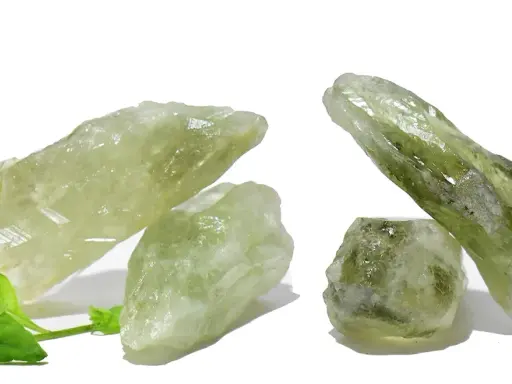 Cristalli grezzi di ametista verde, noti per il loro significato di crescita e rinnovamento, su sfondo bianco con foglie verdi.