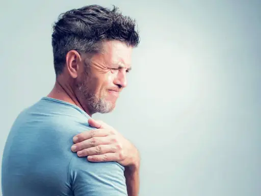 Homme souffrant de douleurs articulaires à l'épaule, possiblement liées à une carence en vitamine B12.