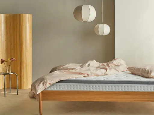 Una habitación nórdica con cama de madera, ropa de cama rosa y un biombo de bambú.