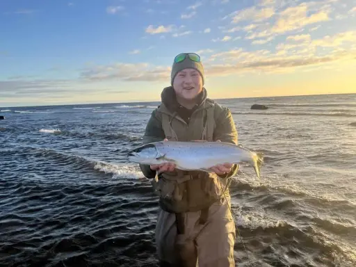Glad fiskare med en fin öring vid havet, en lyckad dag med **trout fishing** i Sverige.