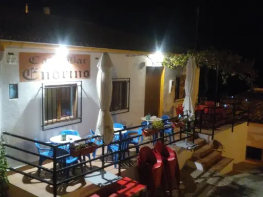 Bar Endrino, un lugar acogedor donde comer en Segura de la Sierra. Mesas y sillas azules y rojas esperan bajo luces cálidas.