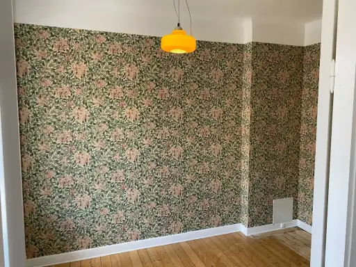 Ett rum med blommig tapet och en gul lampa. Undrar vad kostar det att måla om ett rum?