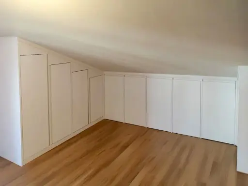 Armadi su misura sfruttano ogni centimetro, perfette idee sottotetto molto basso. Pavimento in legno chiaro.