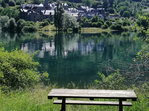 Un banco de madera invita a contemplar el embalse de Lanuza, con un pueblo de tejados grises reflejado en sus tranquilas aguas verdes.