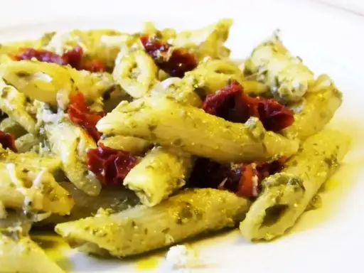 Penne z pesto i kawałkami suszonych pomidorów, posypane parmezanem. Pyszne danie, które zachwyci każdego miłośnika makaronu z suszonymi pomidorami.