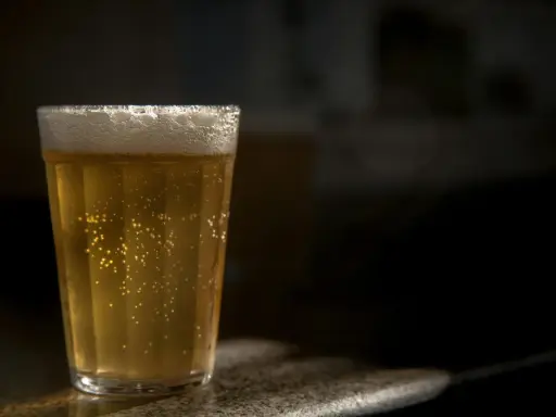 Szklanka złocistego piwa bezalkoholowego, z obfitą pianką i bąbelkami, idealna dla alkoholika szukającego alternatywy.