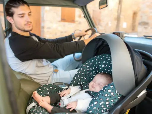 Padre atento conduce mientras su bebé duerme plácidamente en su silla de auto, listo para viajar con bebes.