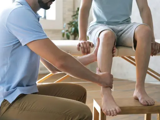 Un podologue examine la jambe d'un patient, un examen essentiel pour la podologie.