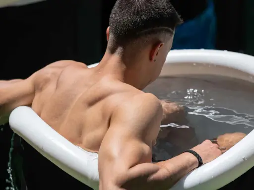 Mann sitzt im Eisbad, bereit für das warme Duschen danach.
