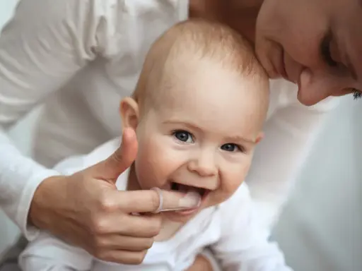 Mama pomaga dziecku z kolejnością wychodzenia zębów, delikatnie masując dziąsła palcem w nakładce.
