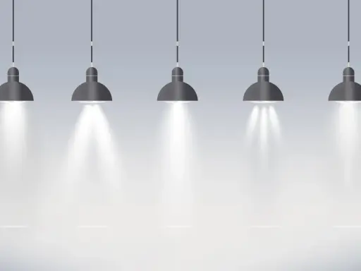 Pięć wiszących lamp tworzy oświetlenie miejscowe, rzucając snopy światła na pustą przestrzeń.
