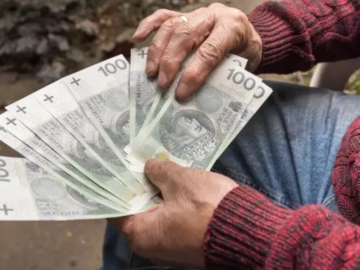 Dłoń trzyma wachlarz banknotów 100 zł. Czy to uczciwy zarobek, czy szalbierstwo?