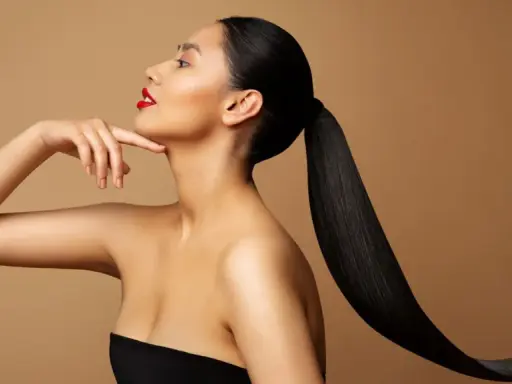 Frau mit glänzendem, schwarzem Pferdeschwanz und rotem Lippenstift, die ihren Hals berührt. Ihr **sleek look** unterstreicht ihre Eleganz.