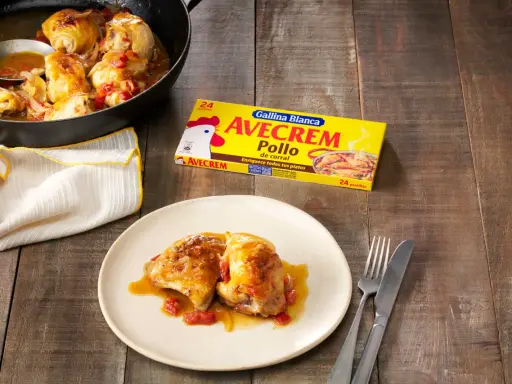 Sabroso pollo con sopa de cebolla y cerveza, servido en sartén y plato. Caja de Avecrem Pollo al lado.