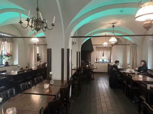 Mysig interiör på Cafe Kronhuset med välvda tak och varma ljus. Två personer sitter vid ett bord och samtalar.