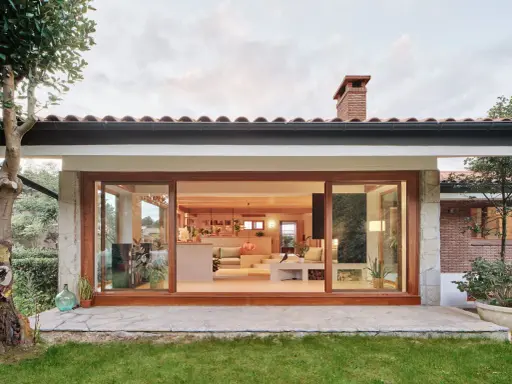Ristrutturazione esterna di una casa anni '70: un'oasi moderna con ampie vetrate che si aprono sul verde.