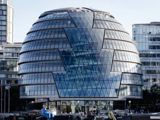 Edificio iconico di Norman Foster, con facciata a diamante in vetro, riflette il cielo e gli edifici circostanti.