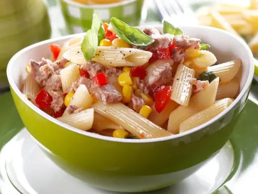 Ein leckerer nudelsalat mit thunfisch, Mais und Paprika, garniert mit Basilikum.