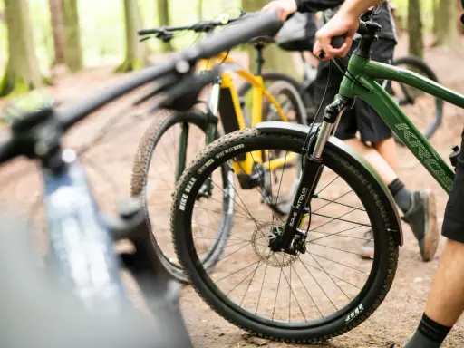 Przygotowania do amatorskich rajdów rowerowych w lesie. Dwa rowery górskie, jeden zielony, drugi żółty, stoją na leśnej ścieżce.