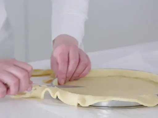 Préparation de la pâte pour une recette biscuit noisette. Les mains ajustent la pâte dans un moule à tarte.