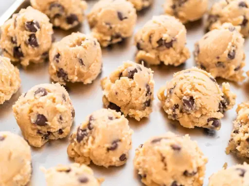 Boules de pâte à cookie au chocolat sur une plaque. Combien de temps la pâte à cookie au frigo se conserve-t-elle ?