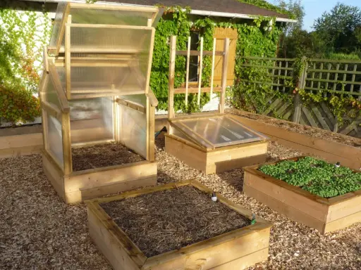 Plusieurs carrés potagers en bois, certains avec des mini-serres, prêts à fabriquer un jardin productif.