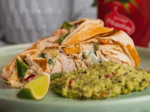 Roladka z tortilli z kurczakiem i warzywami, podana z guacamole i ćwiartką limonki. Idealny sos do tortilli!