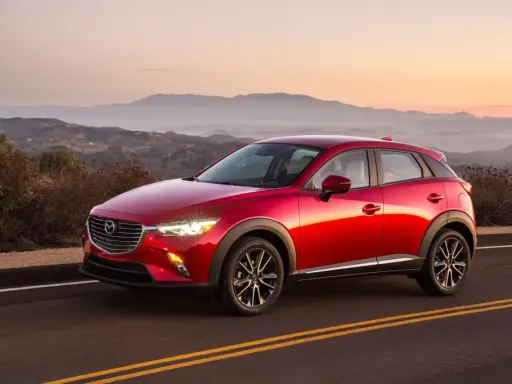 Czerwona Mazda CX-3 na tle górskiego krajobrazu o zachodzie słońca. Elegancka linia nadwozia i lśniący lakier.