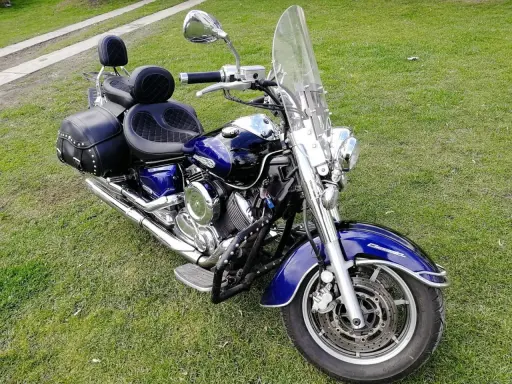 Błyszczący, niebieski motocykl Yamaha Drag Star 1100 z sakwami i dużą szybą, gotowy na podróż. Dane techniczne tego klasyka są imponujące.