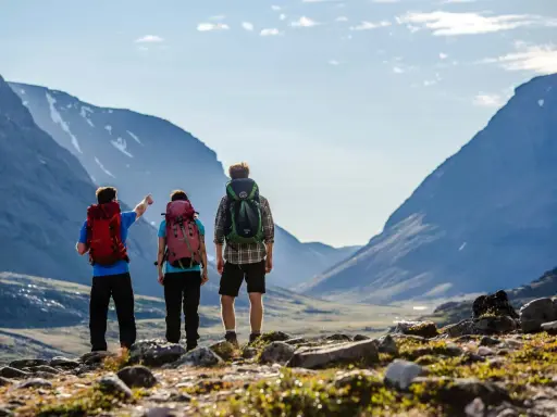 Vandrare med ryggsäckar njuter av den storslagna utsikten över fjällen under en abisko sommar.