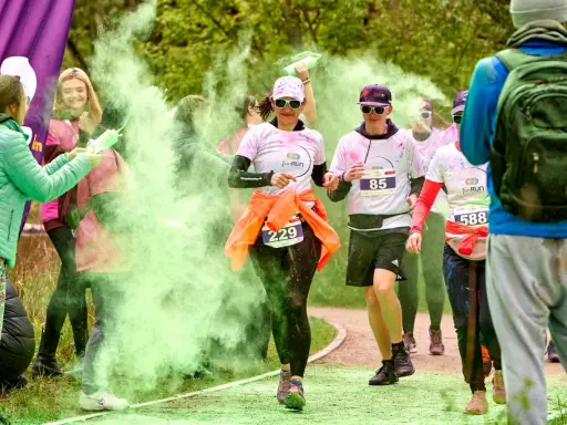 Uczestnicy biegu w kolorowym proszku, w tym 3 forma run, biegną wśród zielonej chmury.
