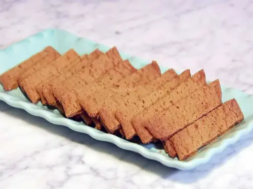 Raka, gyllene kolasnittar med choklad, uppradade på en ljusblå bricka. Perfekta för fikat!
