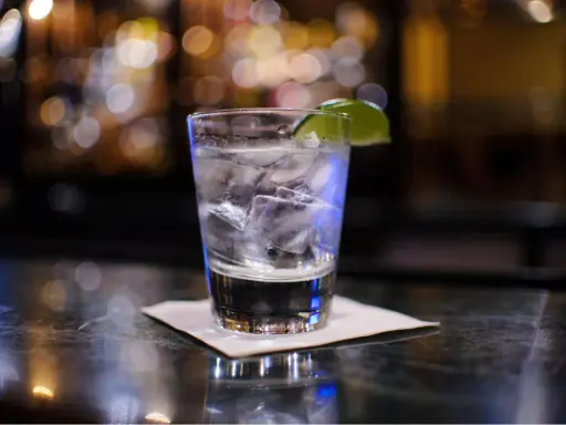 Ein erfrischender Gin Tonic mit Eis und Limette auf einer Bar.
