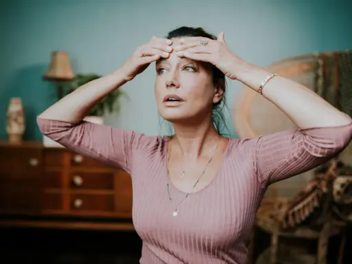 Kobieta wykonuje ćwiczenia na rozluźnienie szczęki, masując czoło.