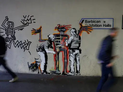 Famous graffiti depicts two police officers interacting with a skeletal figure, with a Keith Haring-esque character and a dog nearby.